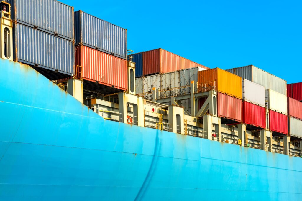 A cargo ship loaded with colorful shipping containers under a clear blue sky, representing maritime trade practices under Incoterms FAS (Free Alongside Ship) and FOB (Free On Board).